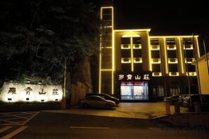 A building with illuminated signage, a parking area, and a vehicle. - Luoxiao Mountain Villa Jinggangshan (Jinggangshan City)