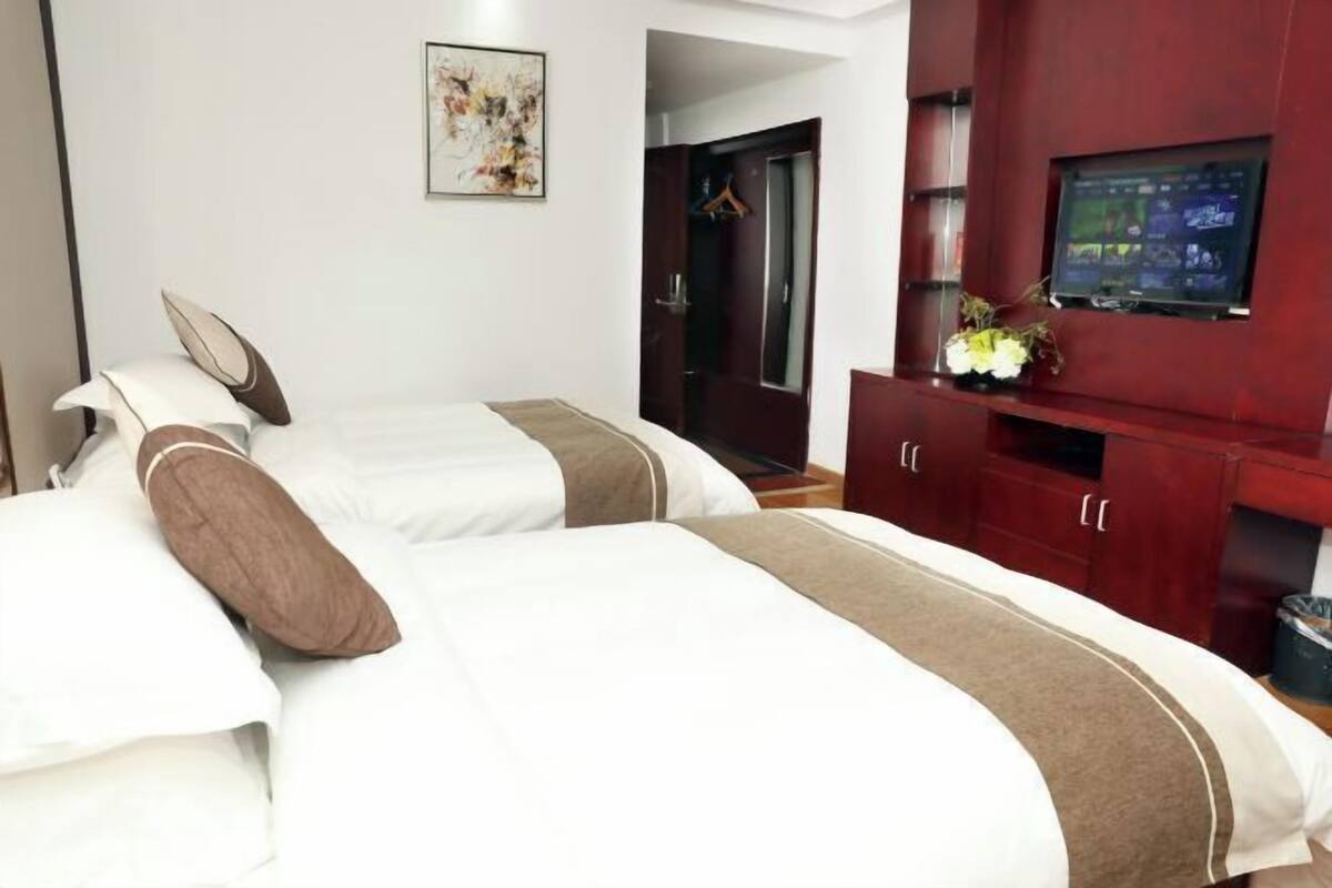 A hotel room with two beds, a TV, and a wardrobe.