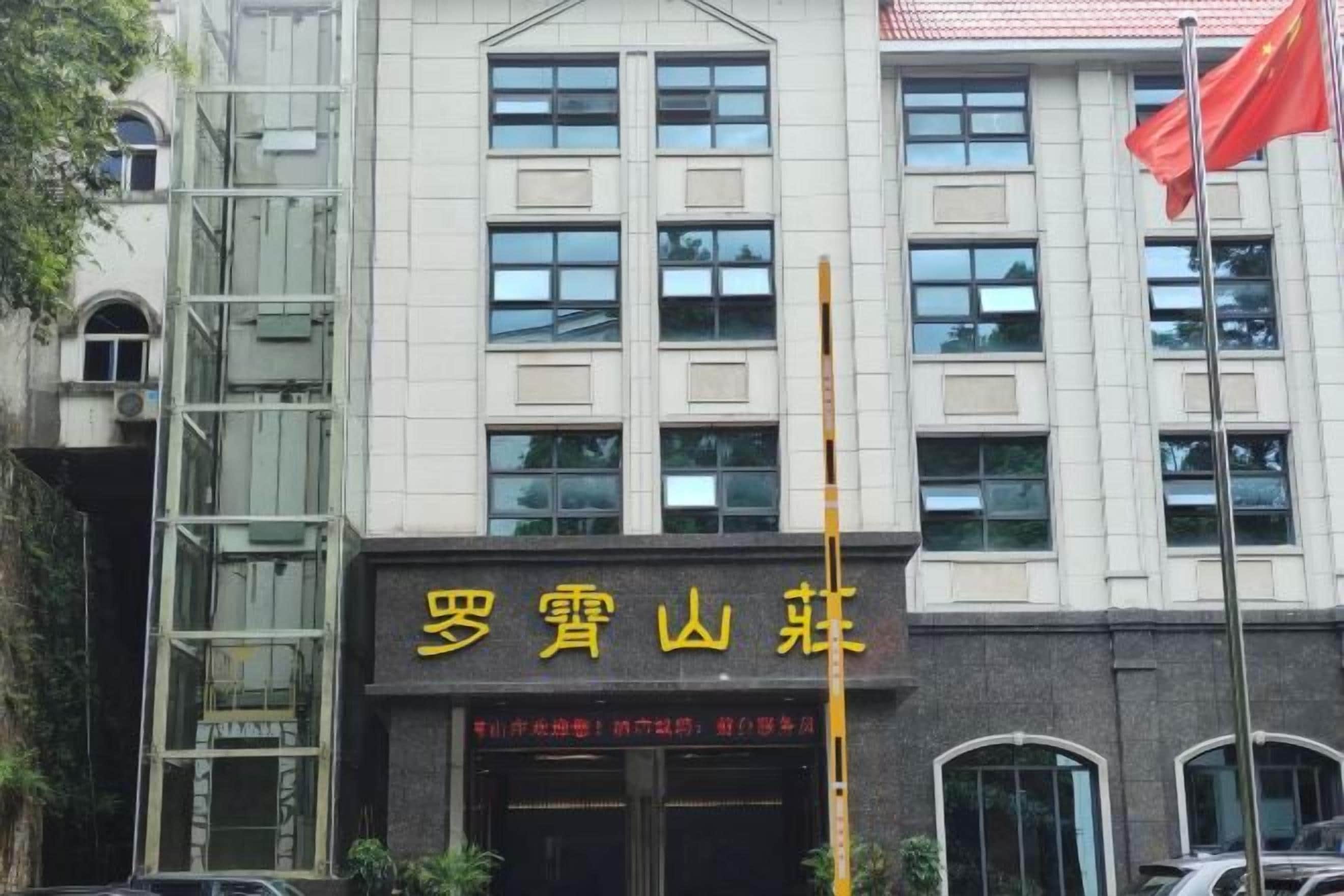 A building with a large sign in yellow characters, a flagpole with a flag, and a staircase on the left side.