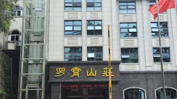 A building with a large sign in yellow characters, a flagpole with a flag, and a staircase on the left side.
