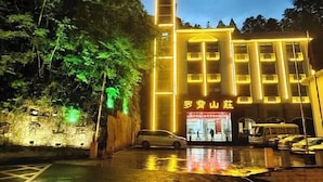 A building with a modern facade, illuminated by yellow lights, and a sign with Chinese characters. - Luoxiao Mountain Villa Jinggangshan (Jinggangshan City)