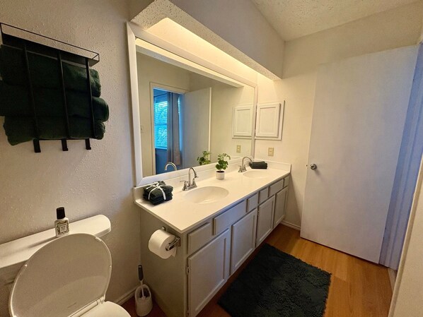 Un baño con un lavamanos blanco, un espejo, un inodoro y un tapete verde oscuro.