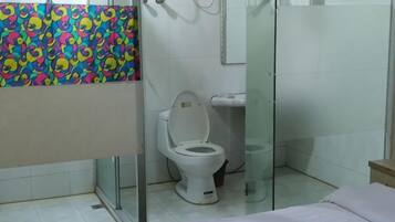 A bathroom with a shower, toilet, and a bed.