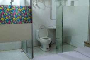 Un baño con ducha, inodoro y cama.
