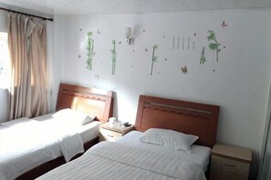 Habitación de hotel con dos camas, una mesita de noche y una pared decorada con pegatinas.