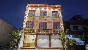 A multi-story building with a ground-level entrance, large windows, and a closed garage door. - Hotel Saurabh Inn (Indore)