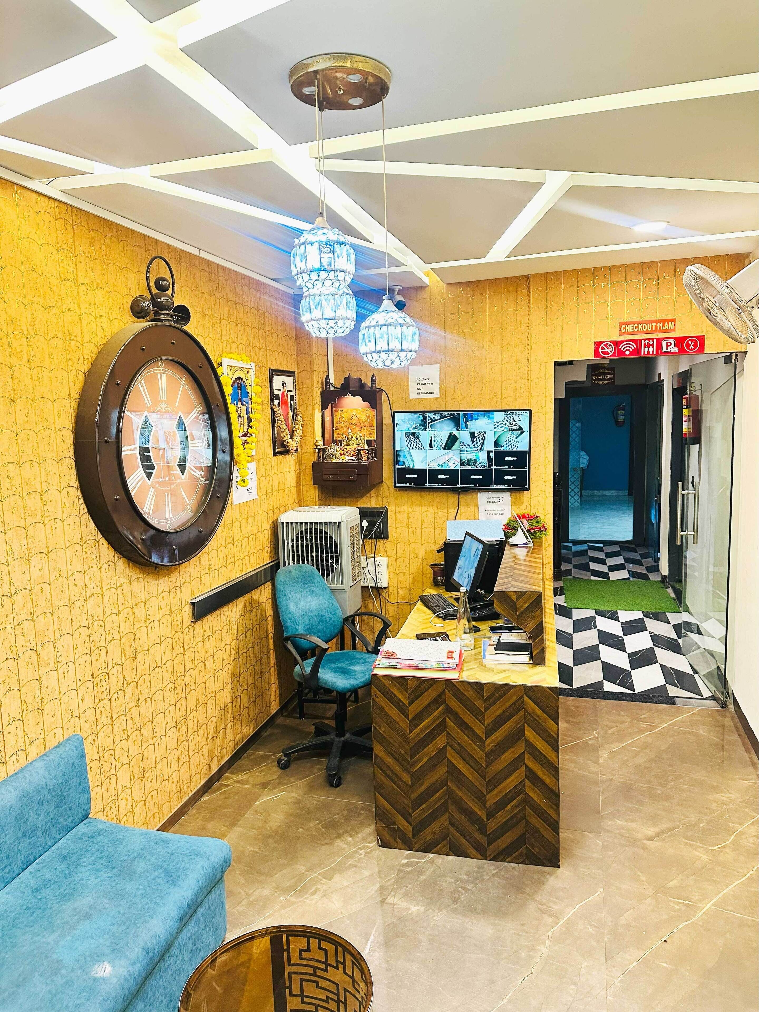 A reception area with a clock, a blue chair, a computer desk, and a check-in counter.