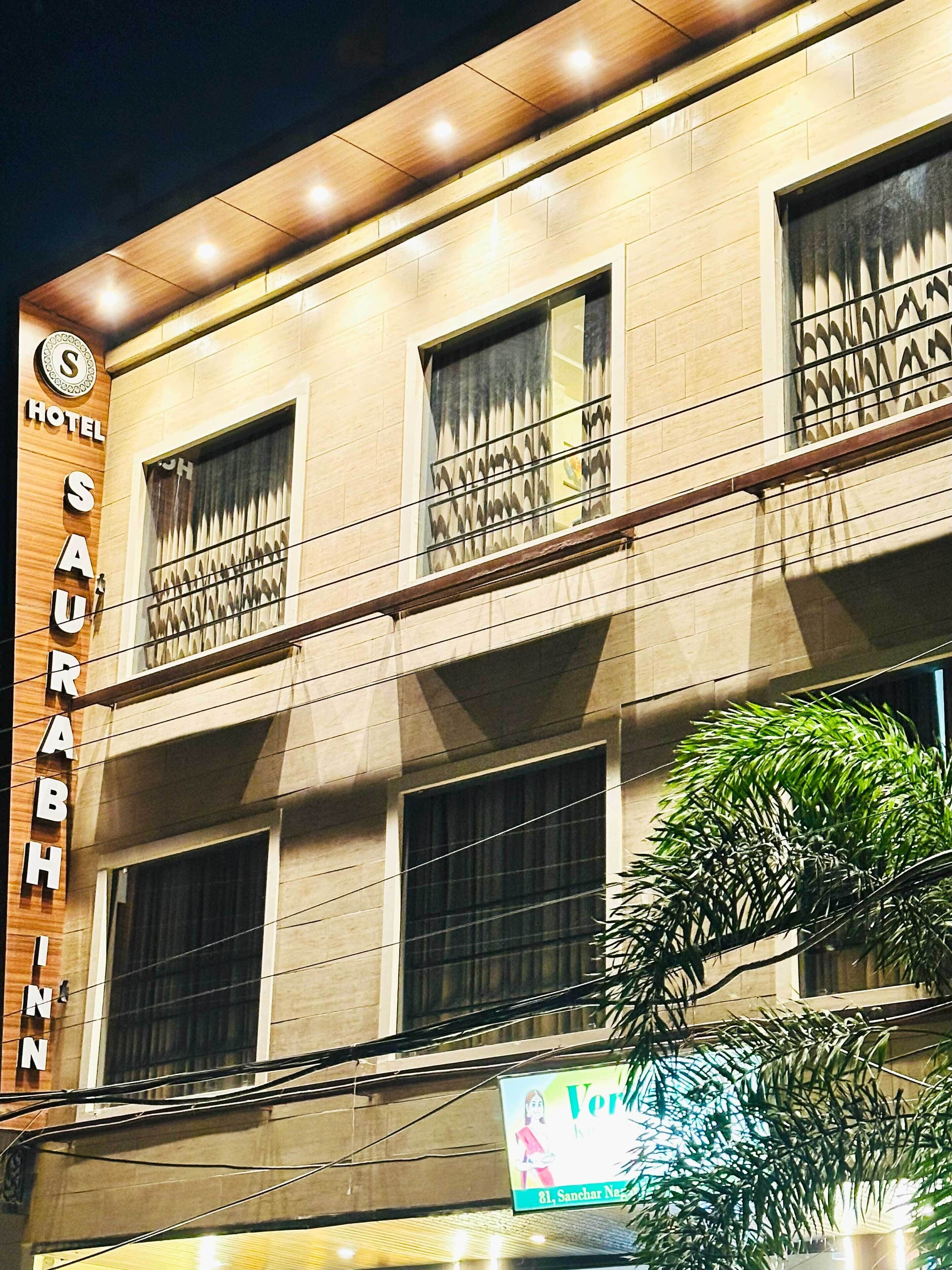 Un hotel con un cartel que dice 'SAURABH INN HOTEL' y la dirección visible '81, Sanchar Naz'.
