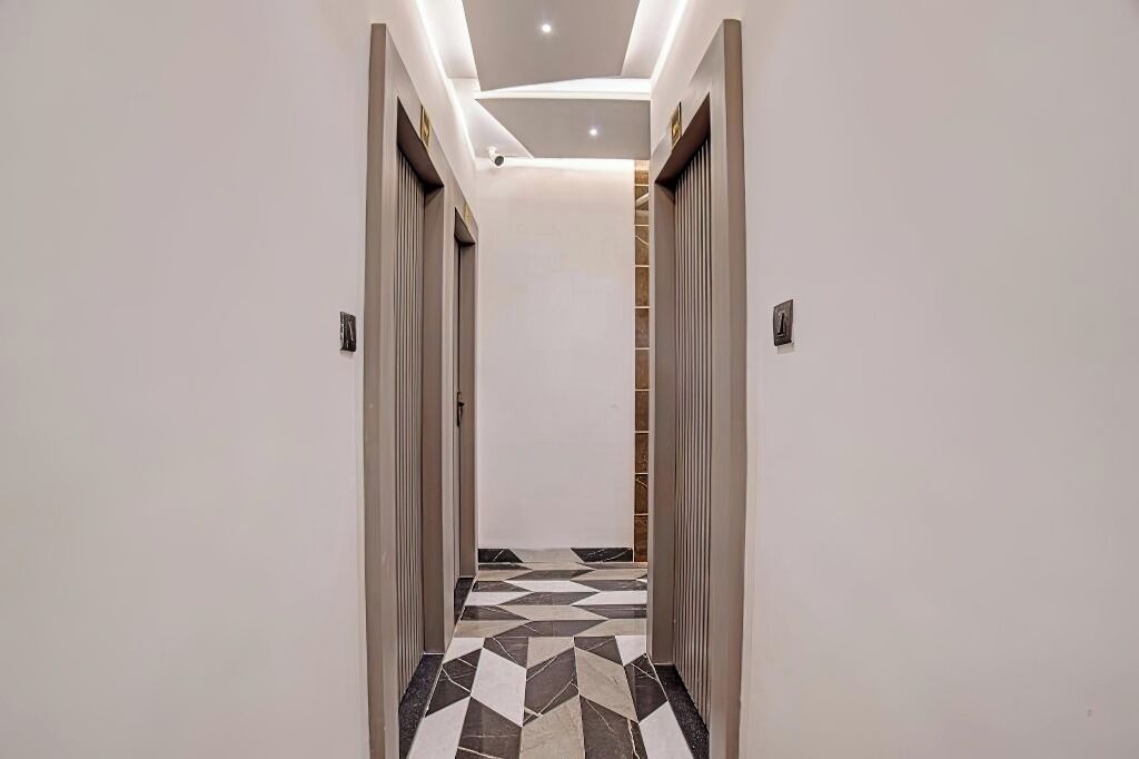Un couloir doté d’un sol à motifs géométriques, de murs blancs et d’un plafond pourvu d’un éclairage encastré.