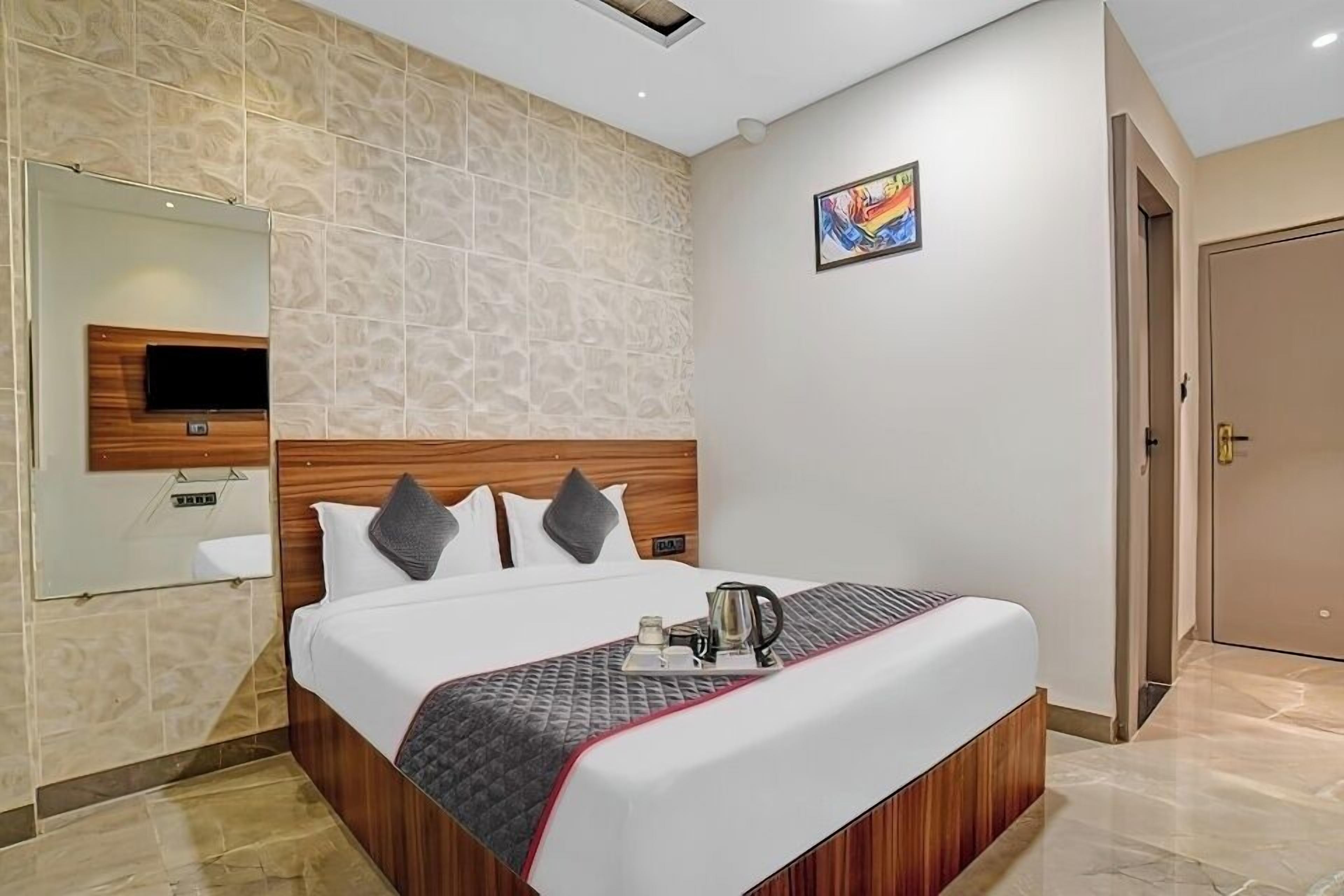 Habitación de hotel con una cama grande, un televisor montado en la pared, un cuadro y una puerta.