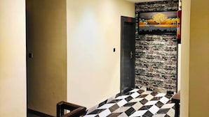 A hallway with a black and white checkered floor, a modern ceiling design, and a wall with a nature-themed mural. - Hotel Saurabh Inn (Indore)