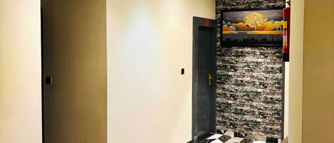 A hallway with a black and white checkered floor, a modern ceiling design, and a wall with a nature-themed mural.
