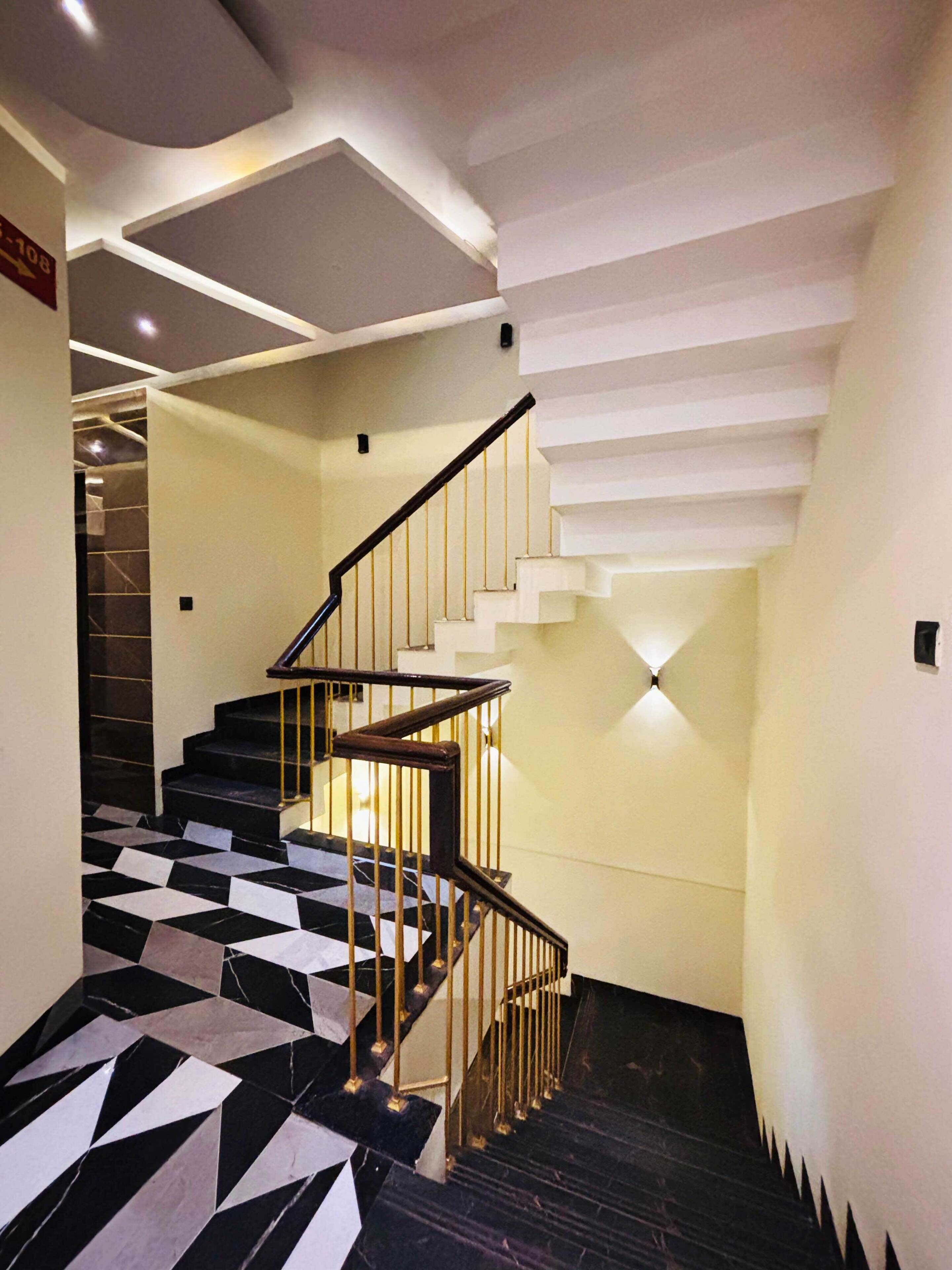 A staircase with black and white patterned flooring, a wooden handrail, and a modern design.