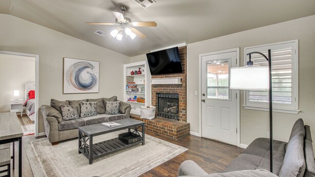 A living room with a sofa, coffee table, fireplace, TV, and a ceiling fan. - 2 Mi to OU: Family-Friendly Retreat w/ Patio! (Norman)
