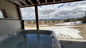 A hot tub with a clear view of a snowy landscape and mountains in the background.