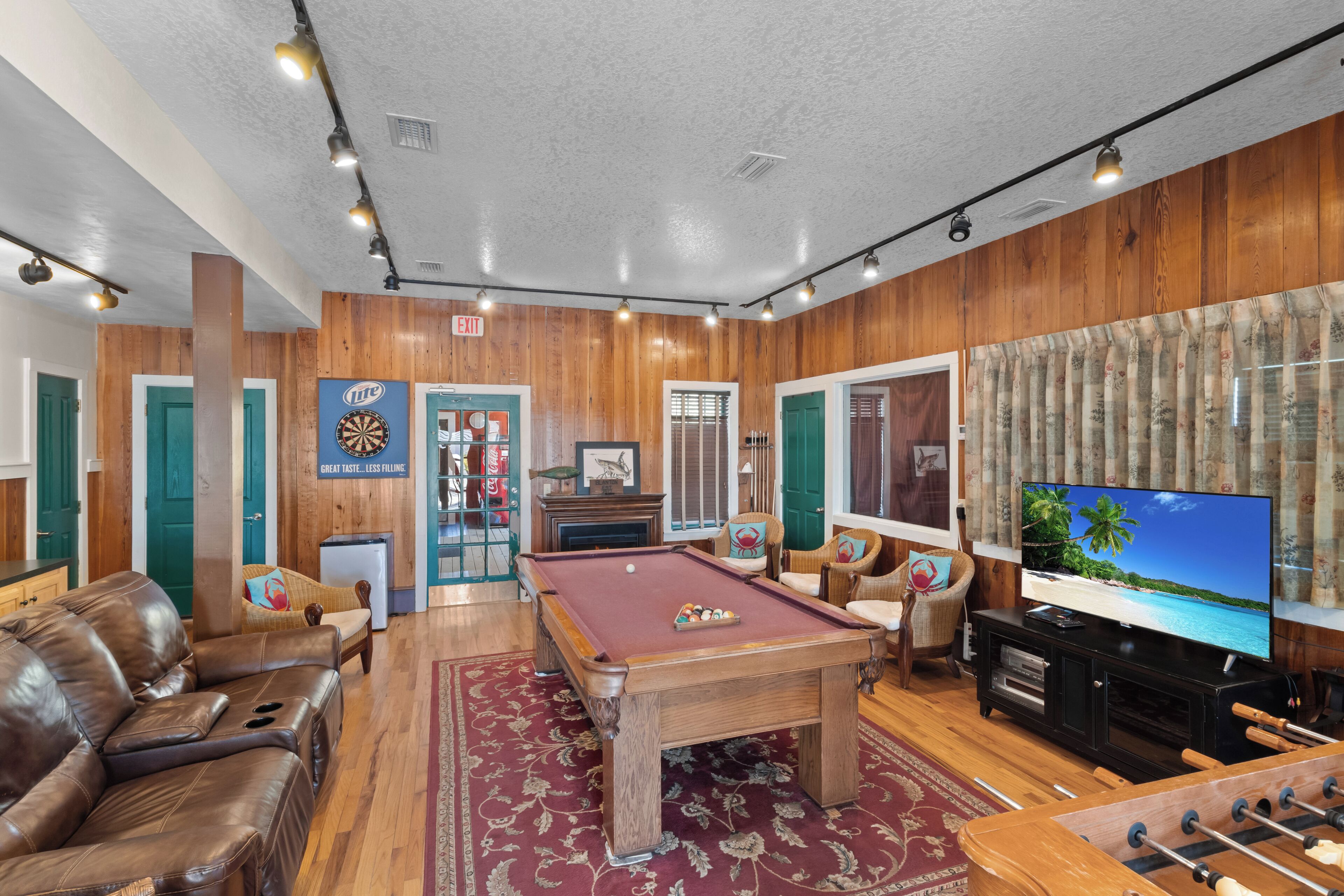A pool table in a room with wooden walls, a television, and a sofa.