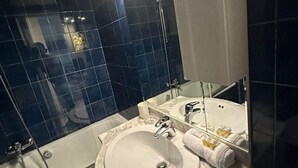 A modern bathroom with a large sink, two mirrors, and a bathtub.