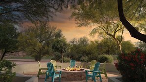 An outdoor seating area with Adirondack chairs around a fire pit.