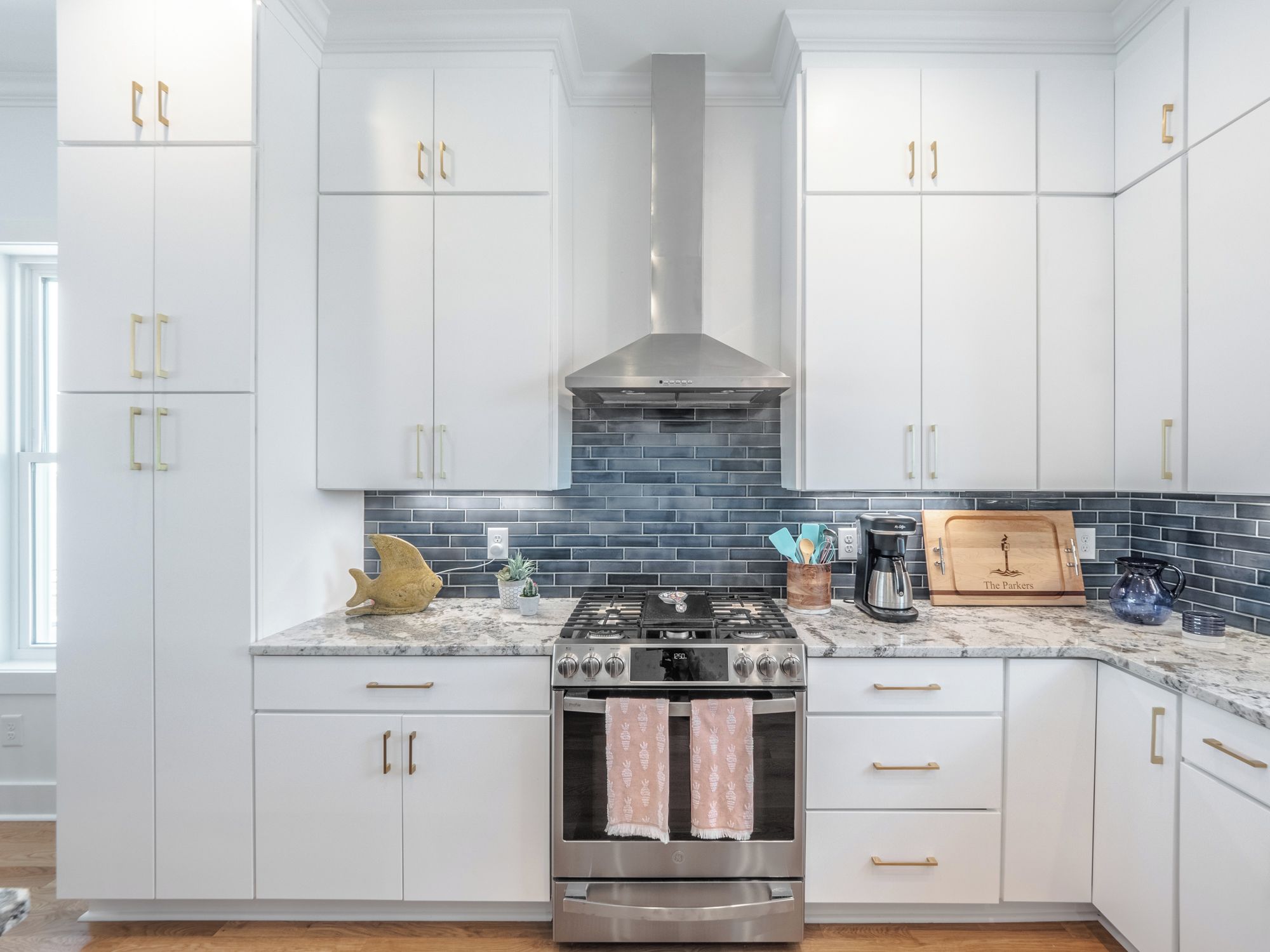 A modern kitchen with white cabinets, a stainless steel stove, and a black tiled backsplash.