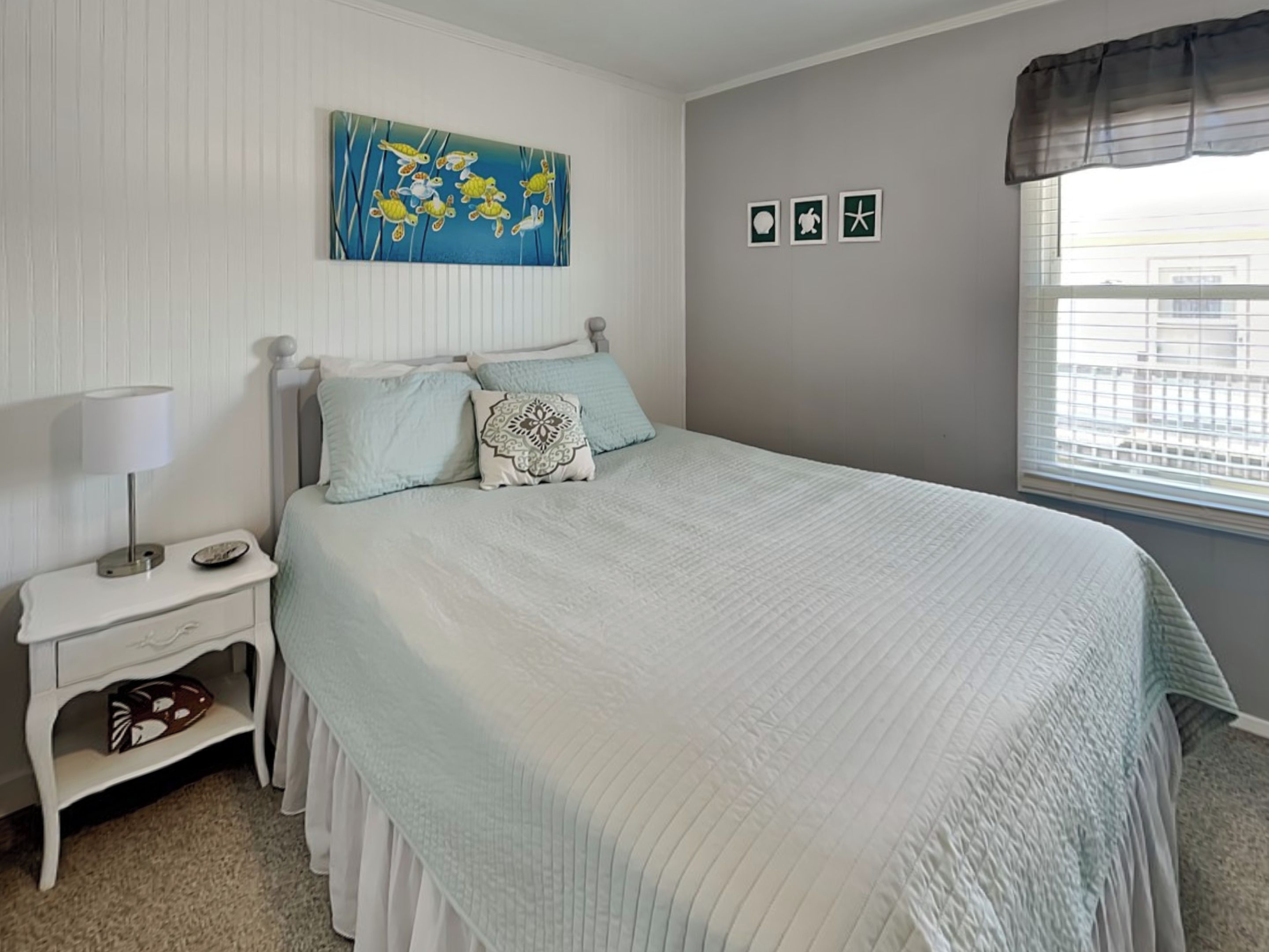 A bedroom with a bed, nightstand, and a window with blinds.