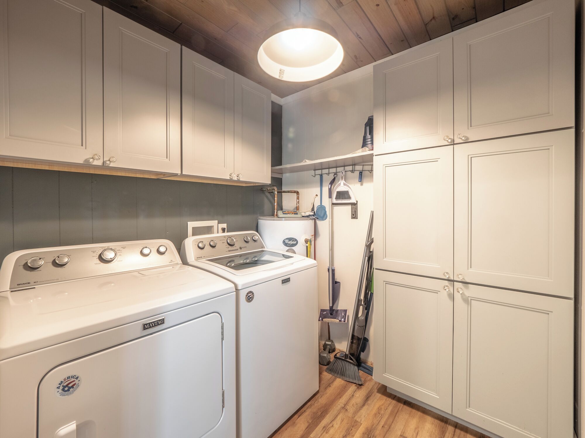 A compact laundry room with a washing machine, dryer, and stacked cabinets.