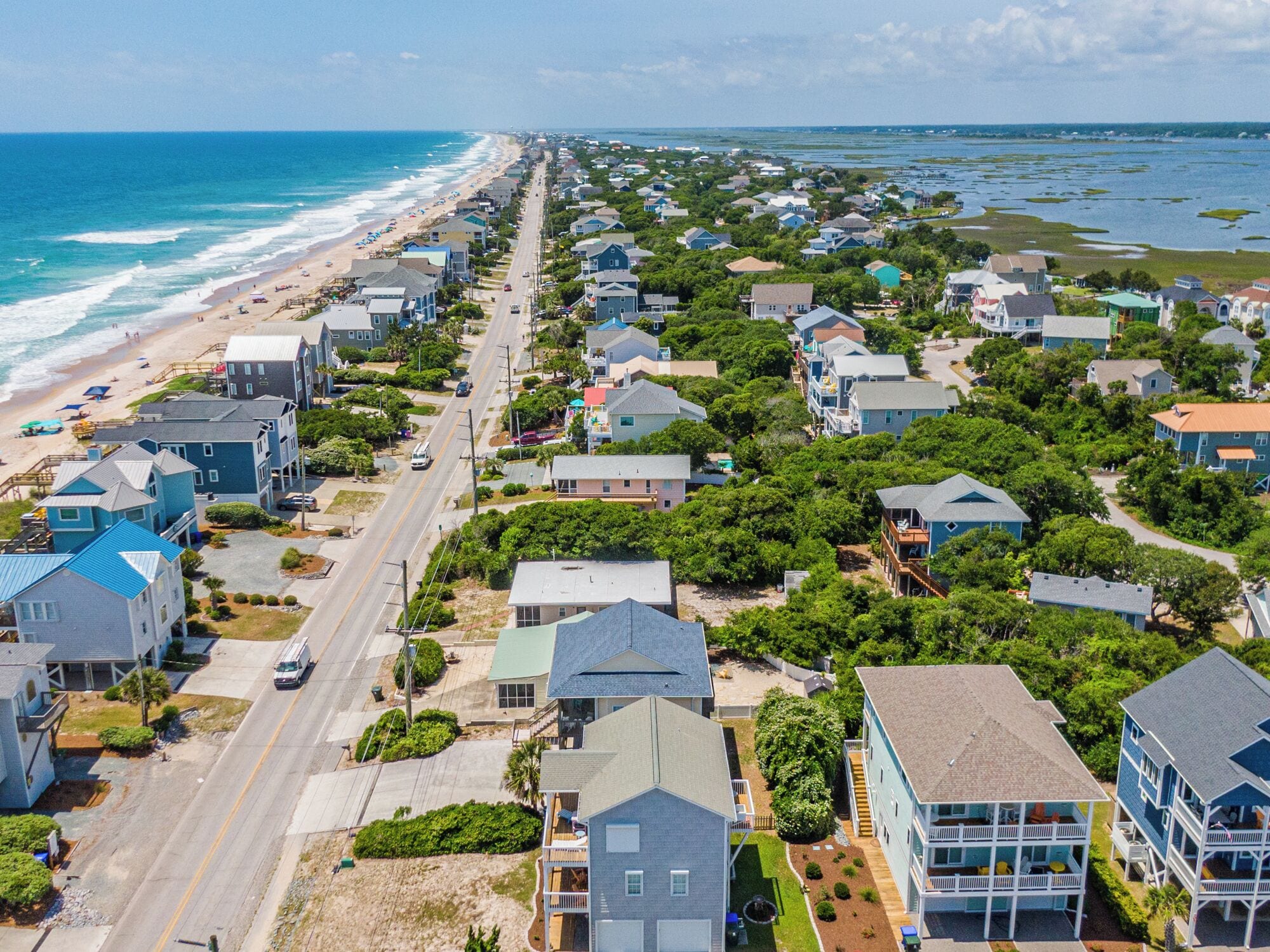 A coastal residential area with houses, a beach, and a road.