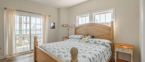 A bedroom with a wooden bed, a nightstand, a ceiling fan, and large windows.