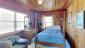 Een kamer met houten lambrisering, een hemelbed, een dressoir, een kaptafel en een raam met gordijnen.