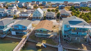 A coastal residential area with houses, a wooden pier, and a view of the ocean. - Seahorse Sound by Topsail Realty (Holly Ridge)