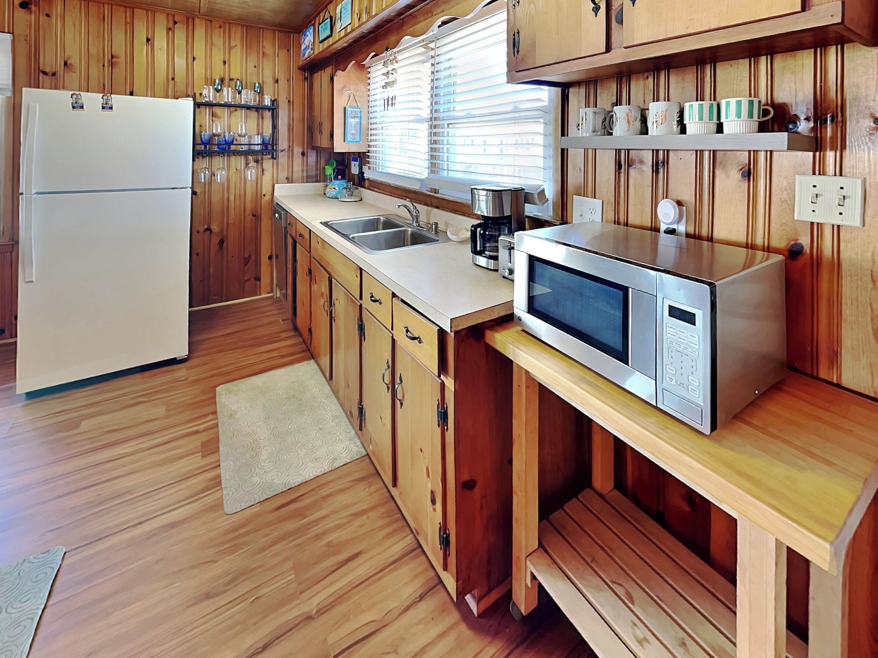 A kitchen with wooden cabinets, a refrigerator, a microwave, a sink, and a coffee maker.