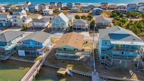 Una zona residenziale costiera con case, un molo di legno e vista sull'oceano.