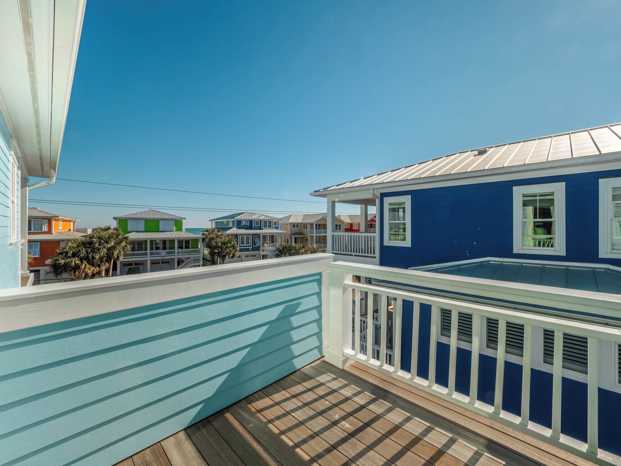 Una casa costera con fachada azul, una terraza de madera y vistas a casas vecinas de colores.