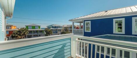 Una casa costera con fachada azul, una terraza de madera y vistas a casas vecinas de colores.