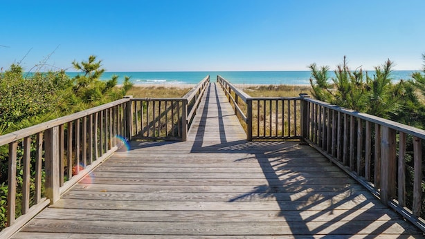 A wooden boardwalk leading to a beach with clear skies. - Blue Oyster by Carolina Retreats (Carolina Beach)