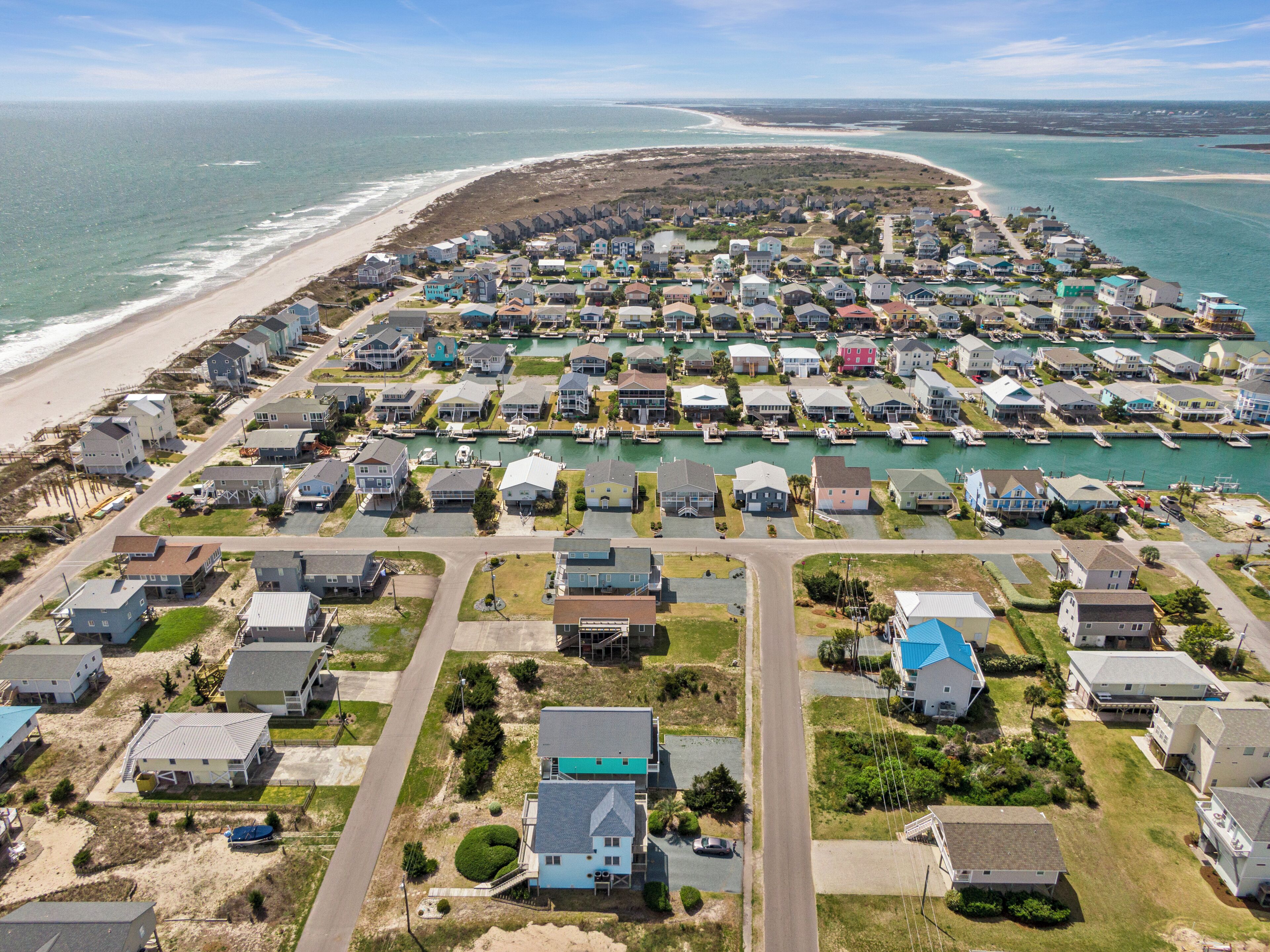 Vista aérea de una zona residencial costera con casas, un puerto deportivo y una playa.