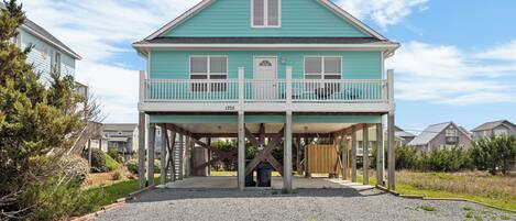 A two-story house with a balcony, a covered porch, and a gravel driveway.