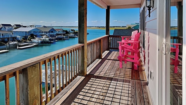 A wooden deck with a view of a marina and houses across the water. - Sunset Nonsense by Topsail Realty (Holly Ridge)