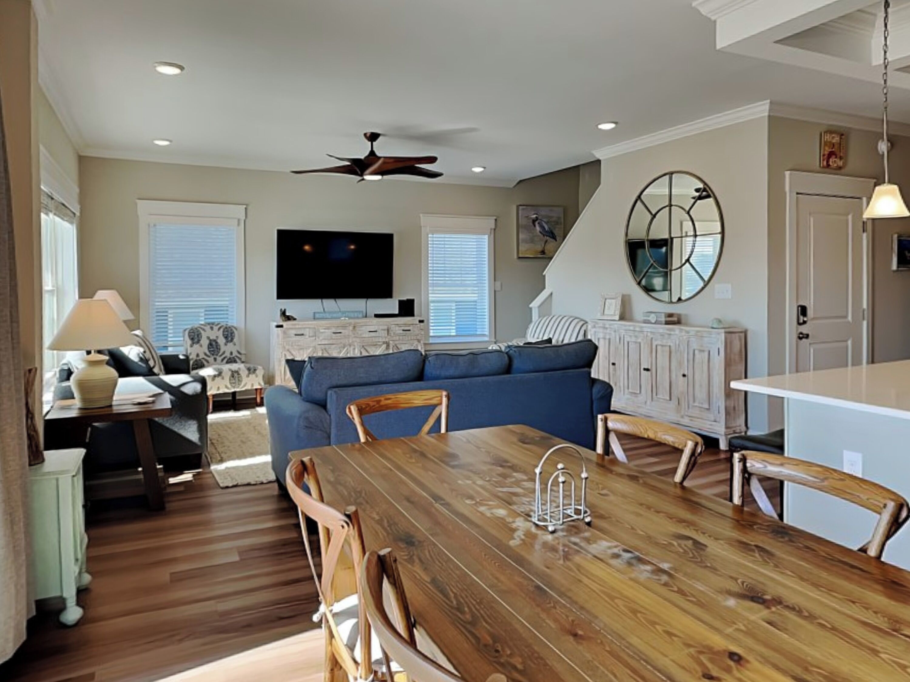 Un salon spacieux avec une table à manger en bois, un canapé bleu et un téléviseur fixé au mur.