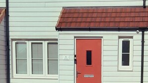 Kaksikerroksinen rakennus, jossa on punainen ovi ja useita ikkunoita.