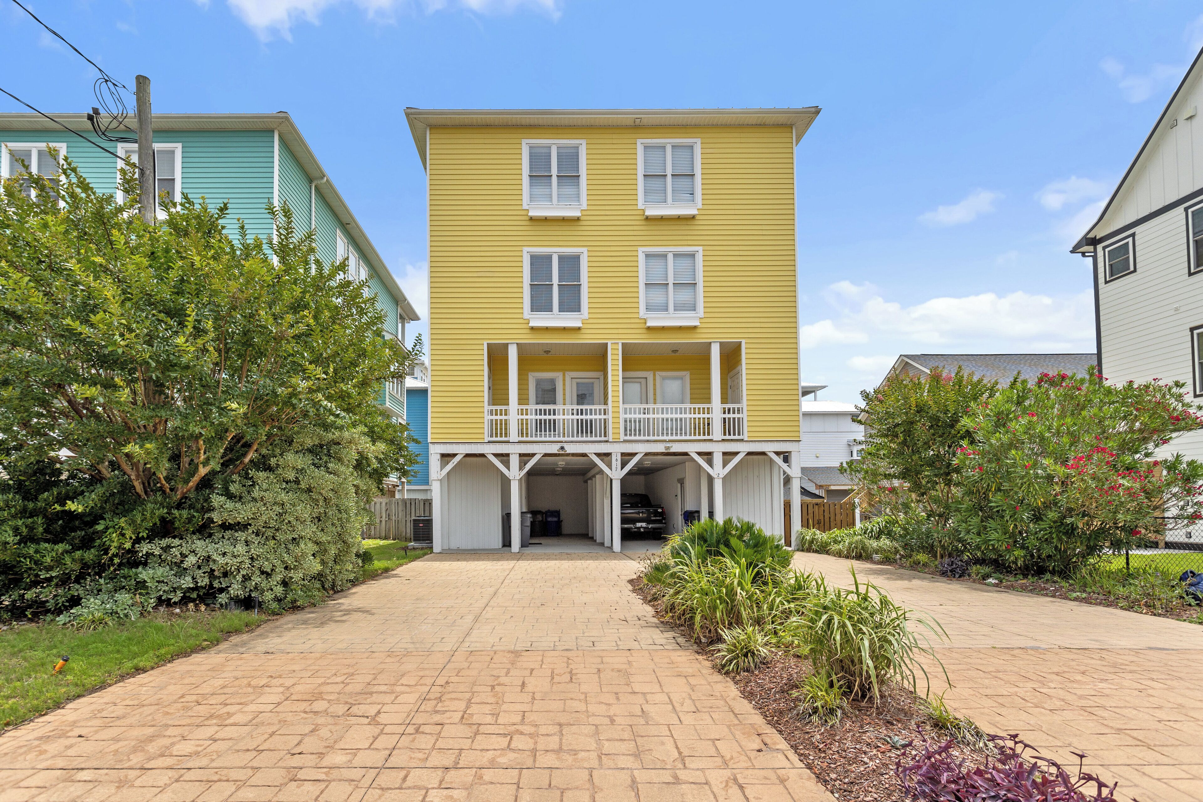 A two-story yellow building with a covered front porch and a garage.