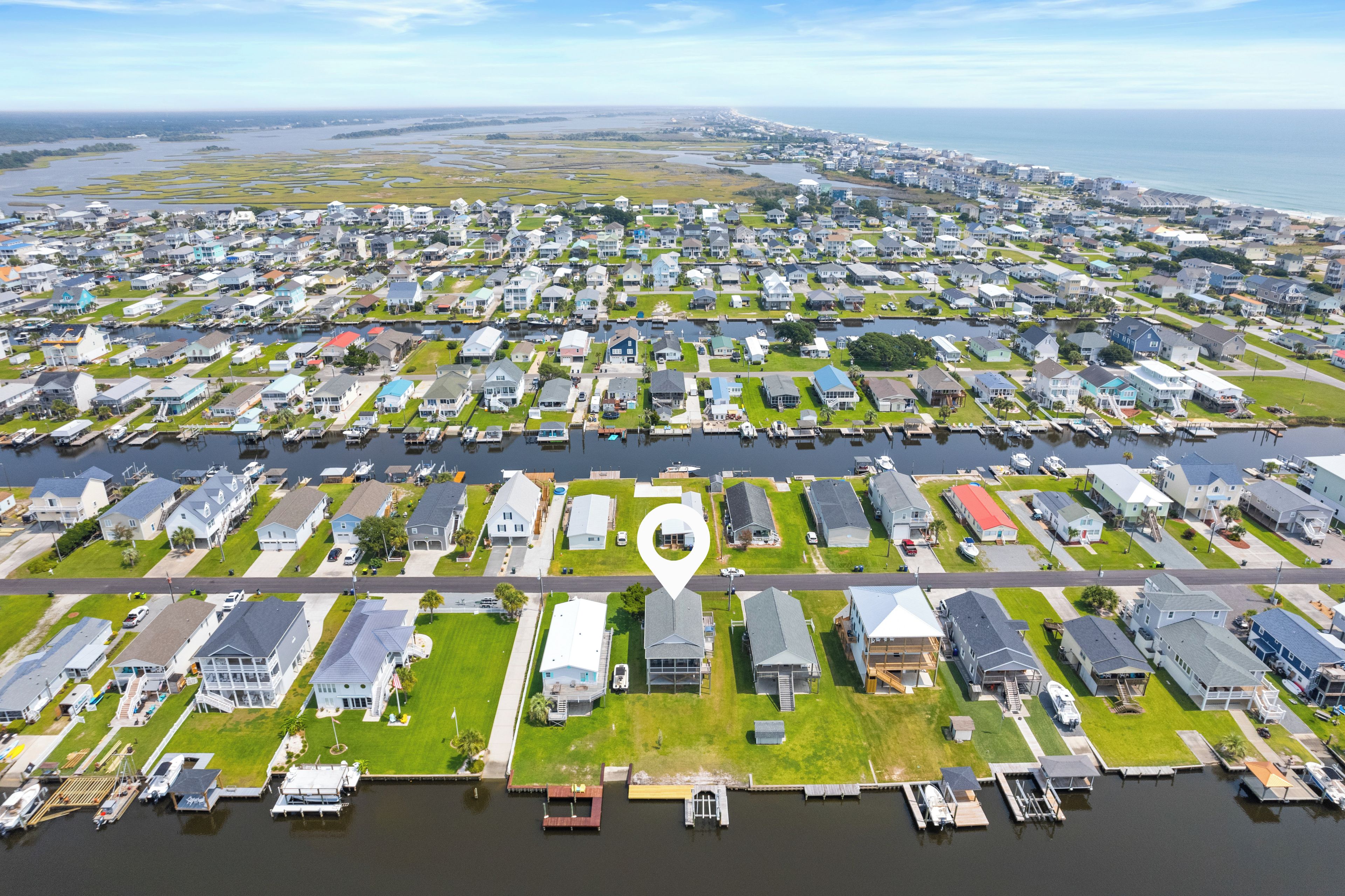 An aerial view of a residential area with houses, a marina, and a large body of water.