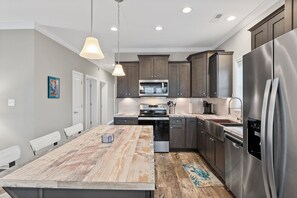 A modern kitchen with a central island, stainless steel appliances, and wooden cabinetry.