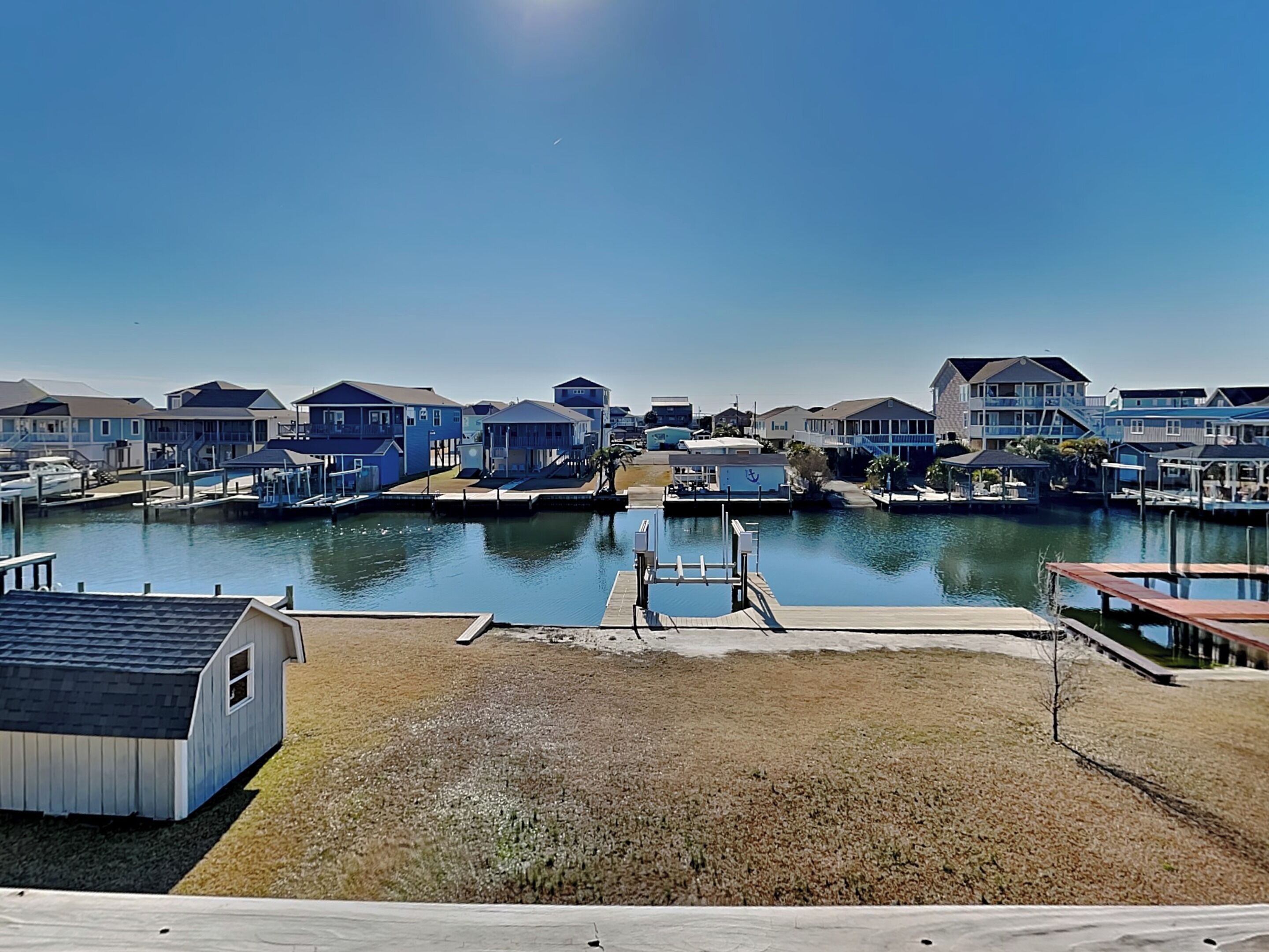 A marina with docked boats, a small shed, and a grassy area.