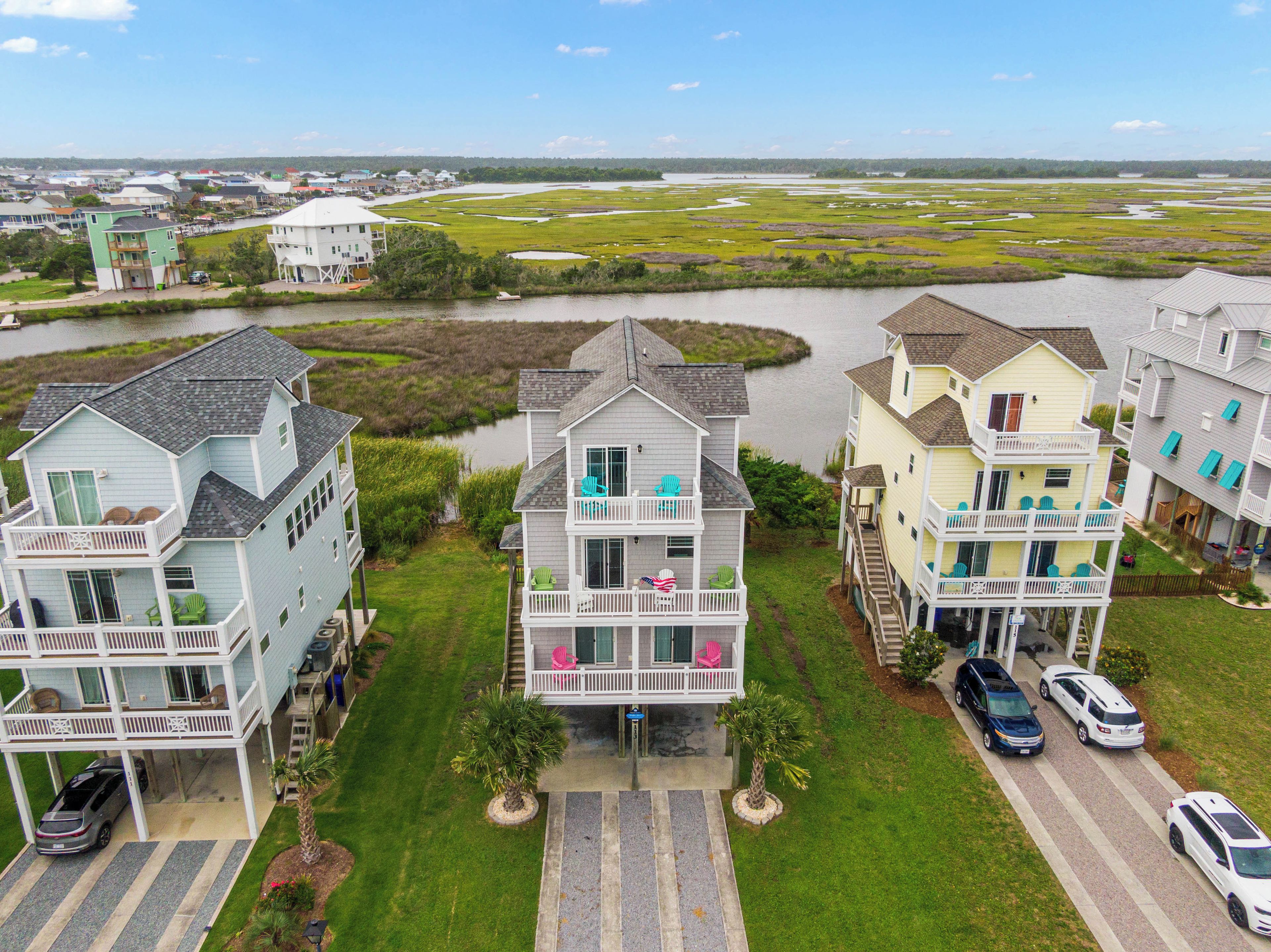 A coastal residential area with multiple two-story houses featuring balconies, a marina, and a marshy landscape in the background.