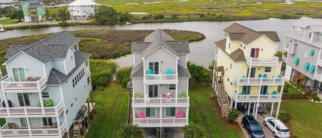 A coastal residential area with multiple two-story houses featuring balconies, a marina, and a marshy landscape in the background.
