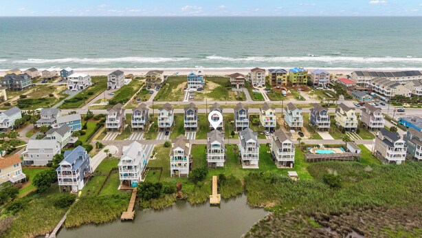 A coastal residential area with houses near the beach, a small water body, and a clear sky. - Palm Beach North by Topsail Realty (Sneads Ferry)