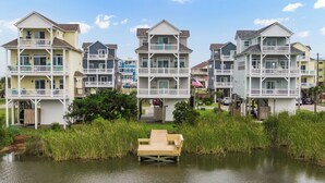 A waterfront residential area with multi-story houses featuring balconies and waterfront views. - Palm Beach North by Topsail Realty (Sneads Ferry)