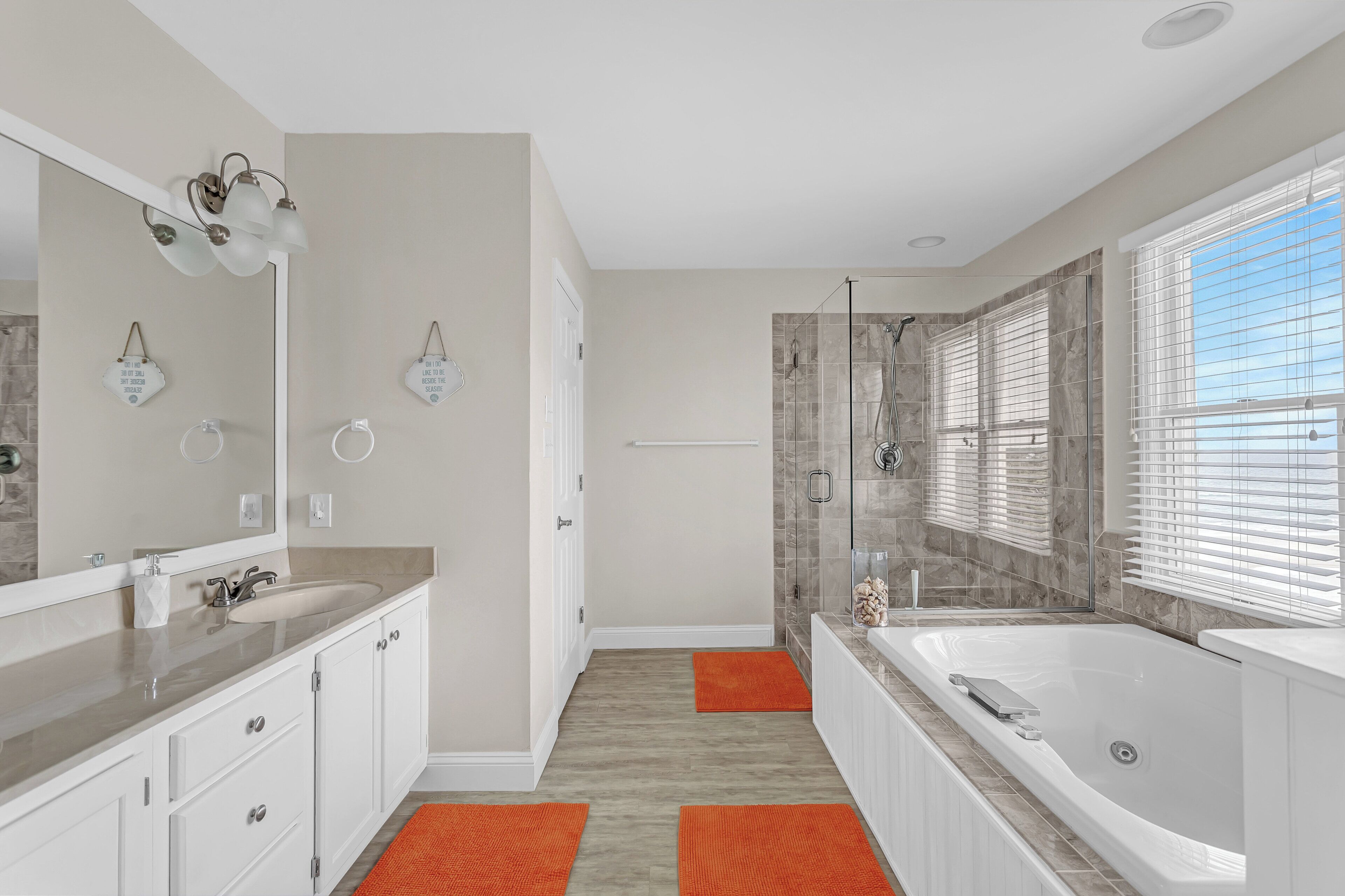 Un baño moderno con un espejo grande, una bañera y zona de ducha.