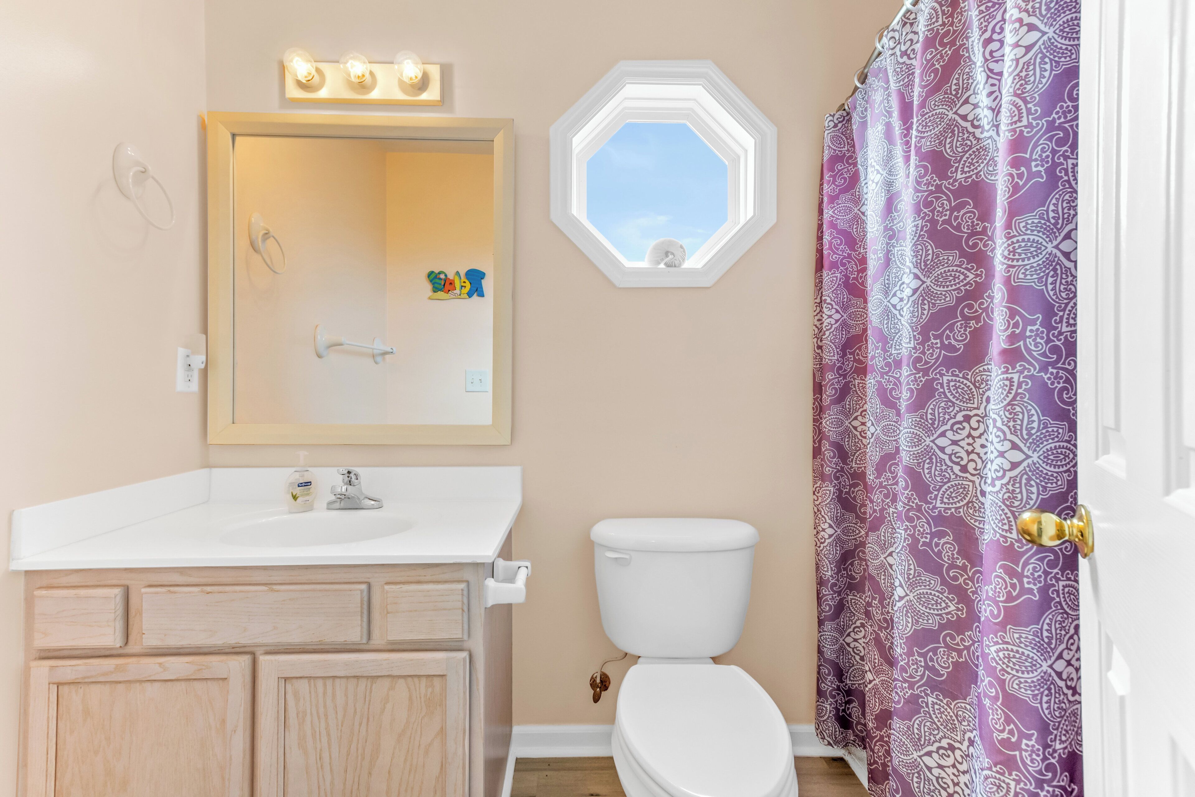 Un baño con lavamanos blanco, un espejo con iluminación, un inodoro y una ventana con vistas.