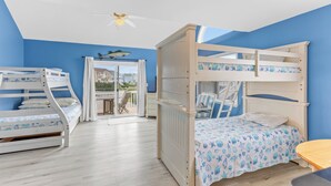 Une chambre avec deux lits superposés, un ventilateur de plafond et une vue sur l’extérieur.